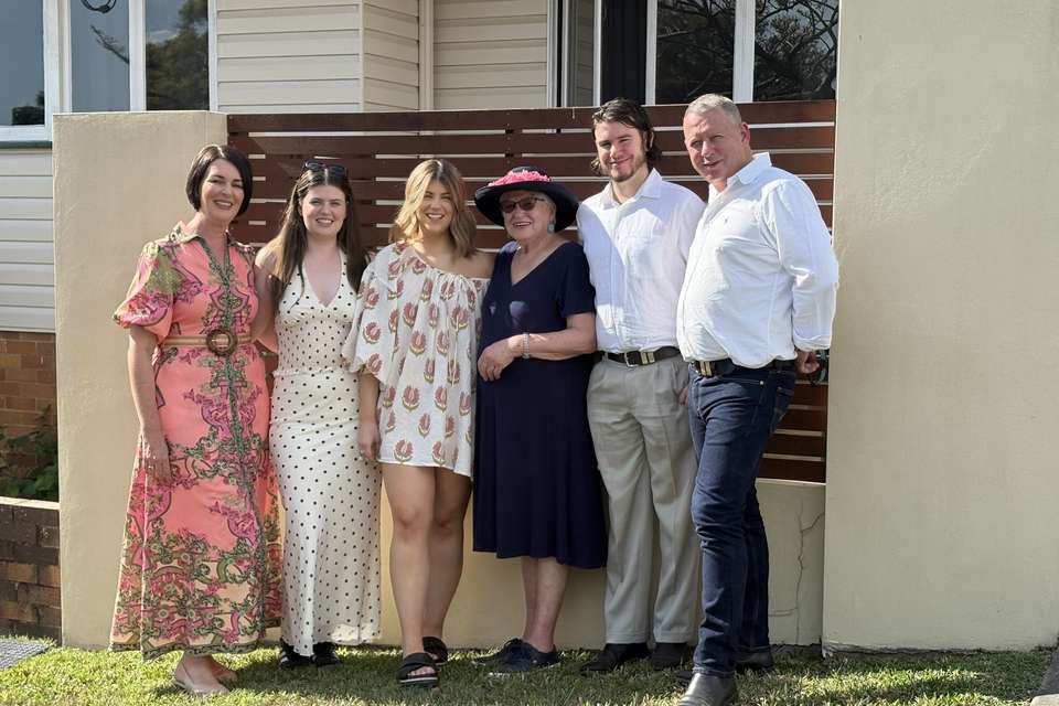 Image of a family group standing in front of house