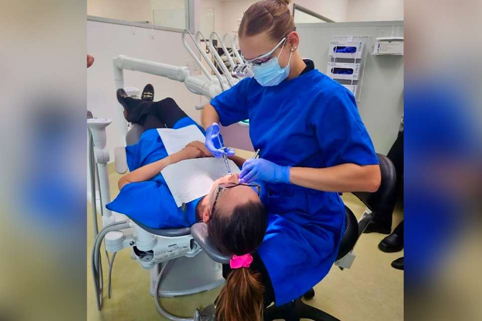 Olivia Arnold as an oral health student, practising treatment on a fellow student in a dental chair