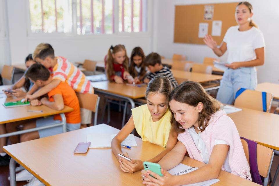 Absorbed interested preteen school children using mobile phones to watch game-based learning materials during lesson in classroom.jpeg