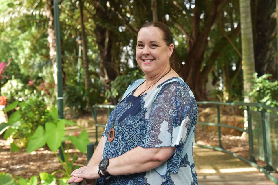 Anne-Maree Scott stands on bridge surrounded by plants and trees.jpg