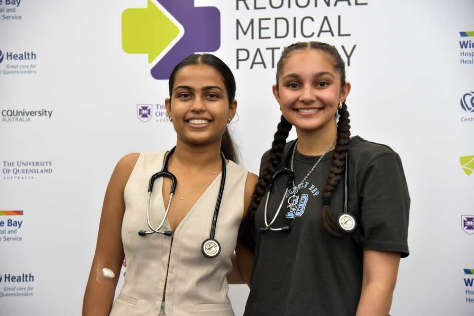 Students Shova Yadav and Ava Prasad in front of a media wall for the Regional Medical Pathway.JPG