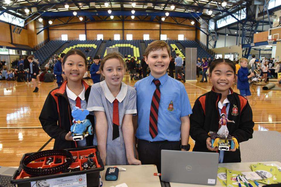 Primary students smiling as they display their robotic creations