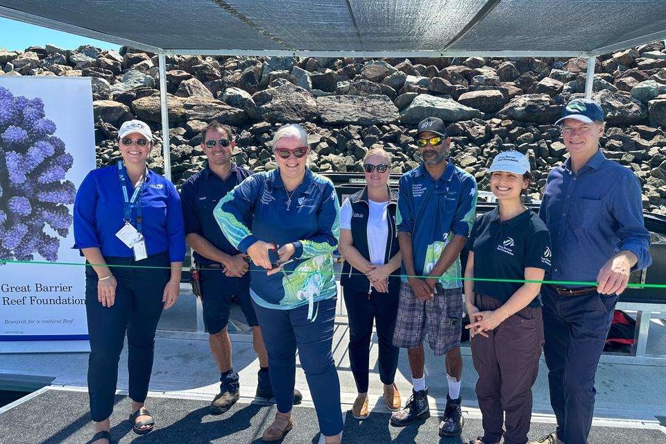 A group of people behind a ribbon that is being cut