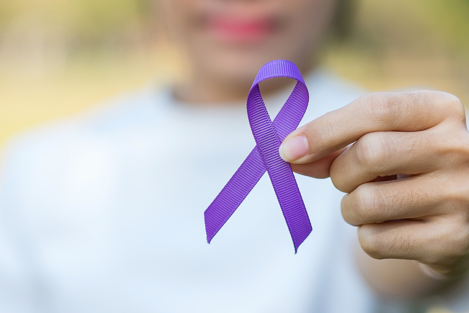 A hand holding a purple ribbon