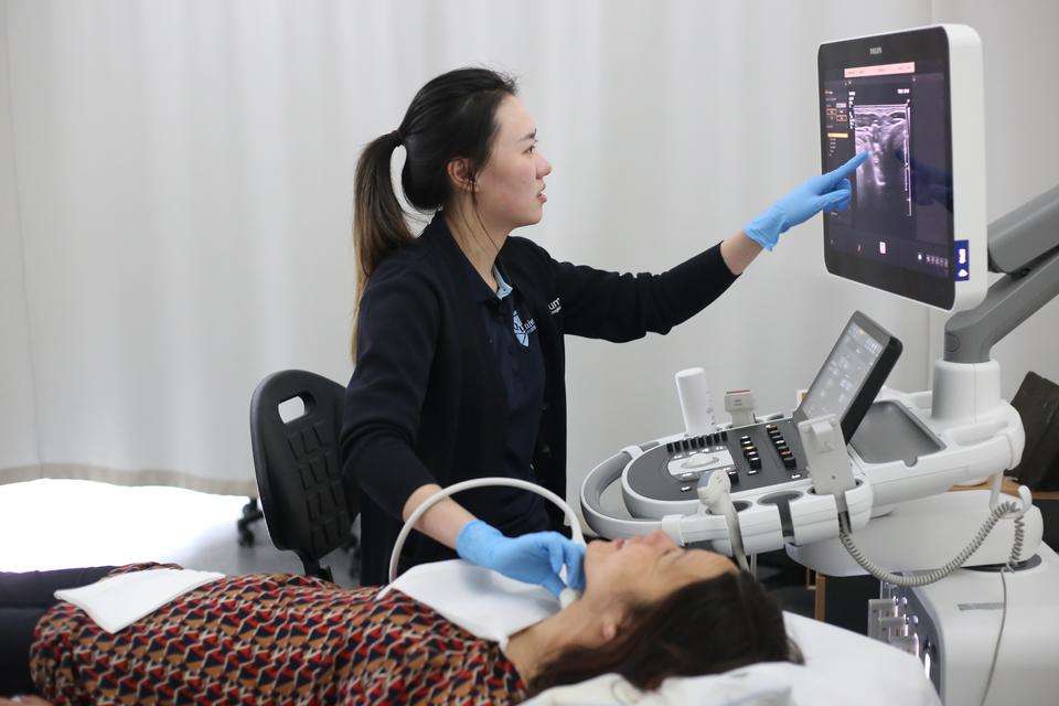 A sonography student uses ultrasound equipment to scan a patient.