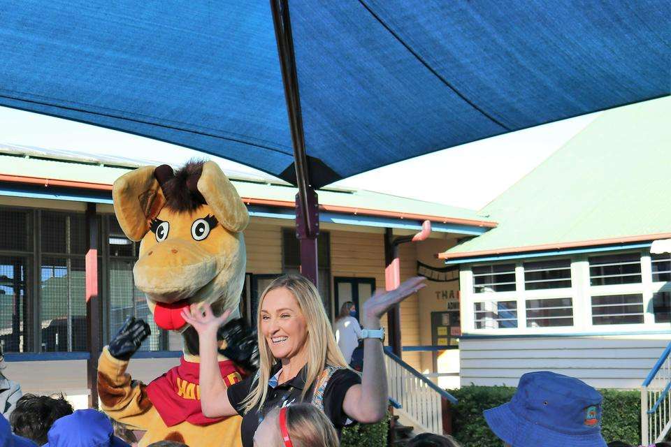 Sue Osmond stands in a school program with Healthy Harold, the giraffe mascot of Life Ed.