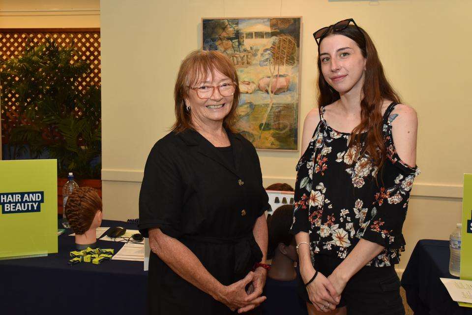 CQU Beauty Therapy teacher Mary Mckenzie and prospective student Kateasha Fritz stand smiling at the camera by the Hair and Beauty stall at the TAFE Careers Expo