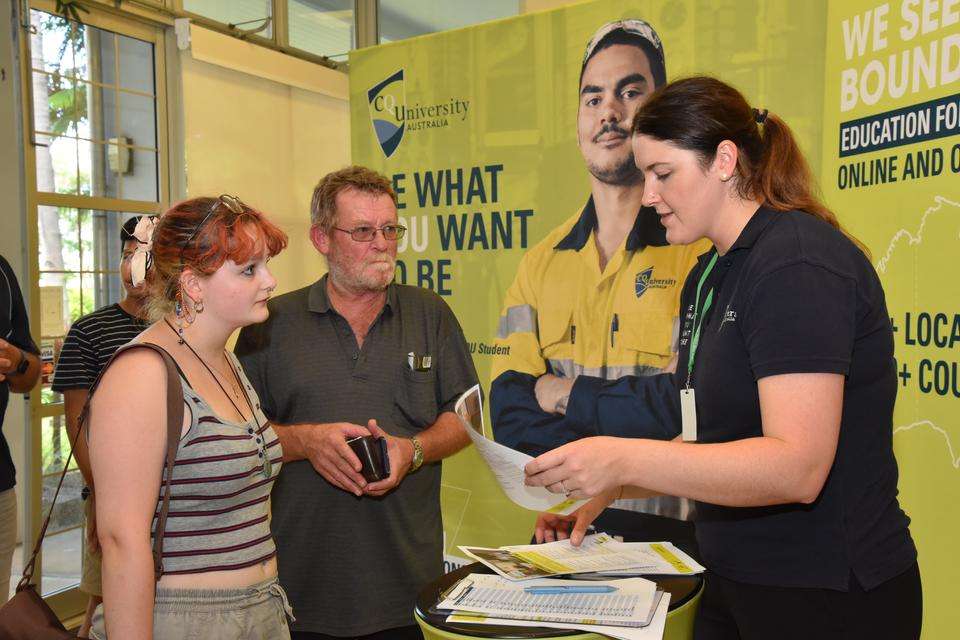 CQU staff member assists expo attendees with information leaflets