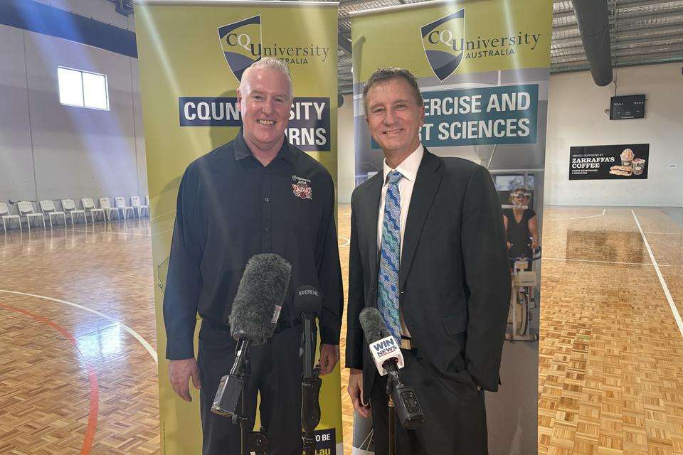 Taipans CEO and CQUniversity VC on a basketball court in front of CQU banners