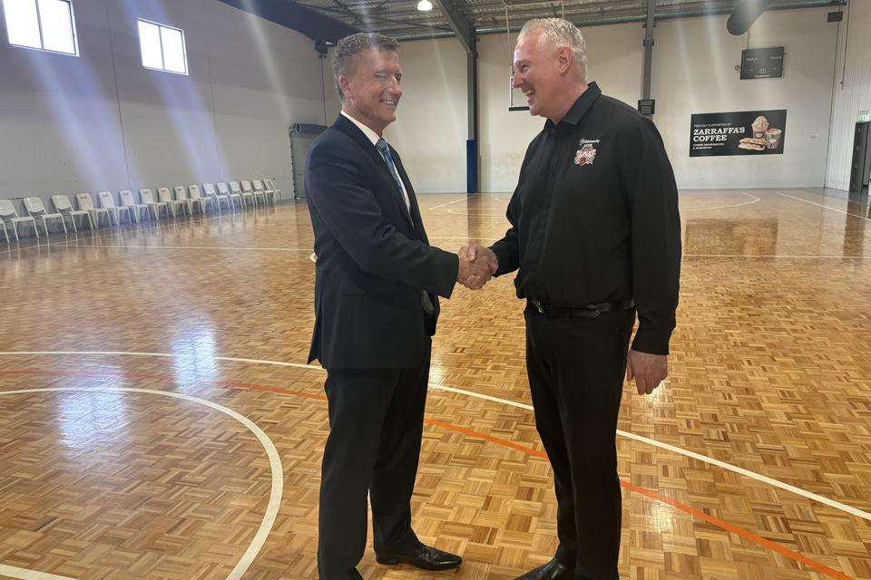 CQU VC Nick Klomp and Cairns Taipans CEO Mark Beecroft shaking hands on a basketball court