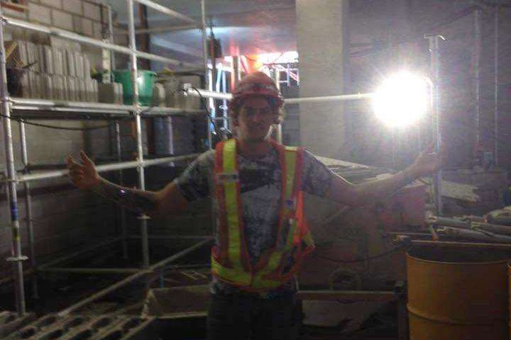 A young man in a hi-visibility shirt and hardhat in a basement construction site