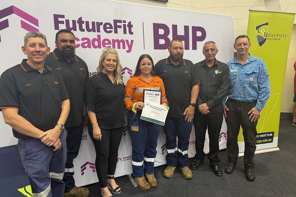 A group of people standing in front of two large banners which read BHP Future Fit Academy and CQUniversity Australia