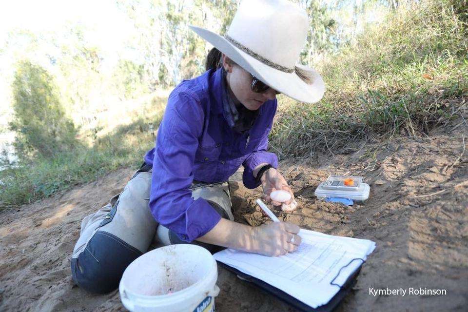 Researcher Kymberly Robinson recording data. on the banks of a riverjpg