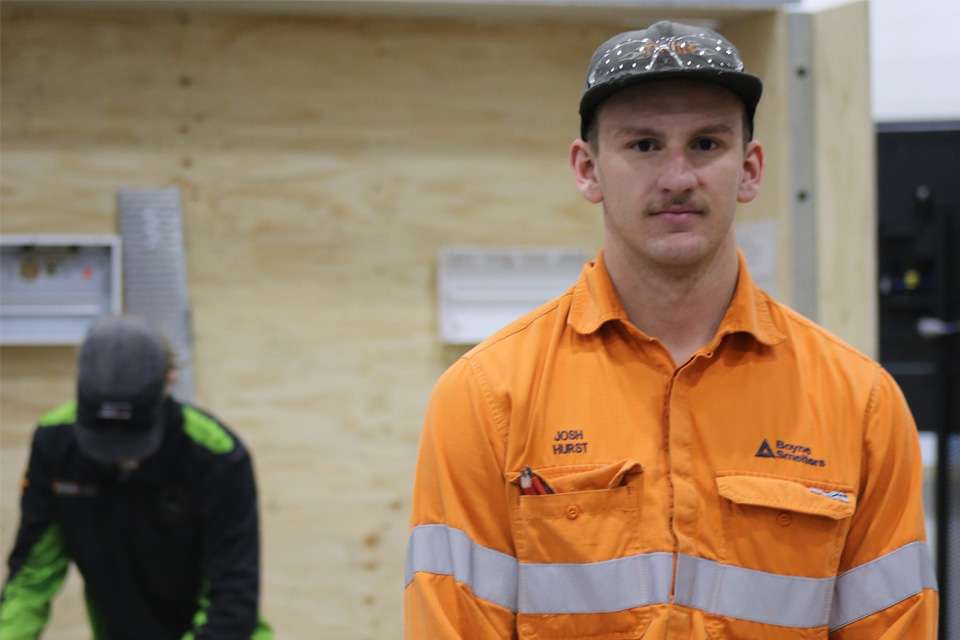 Image of a man wearing a baseball cap and orange hi-viz shirt facing the camera