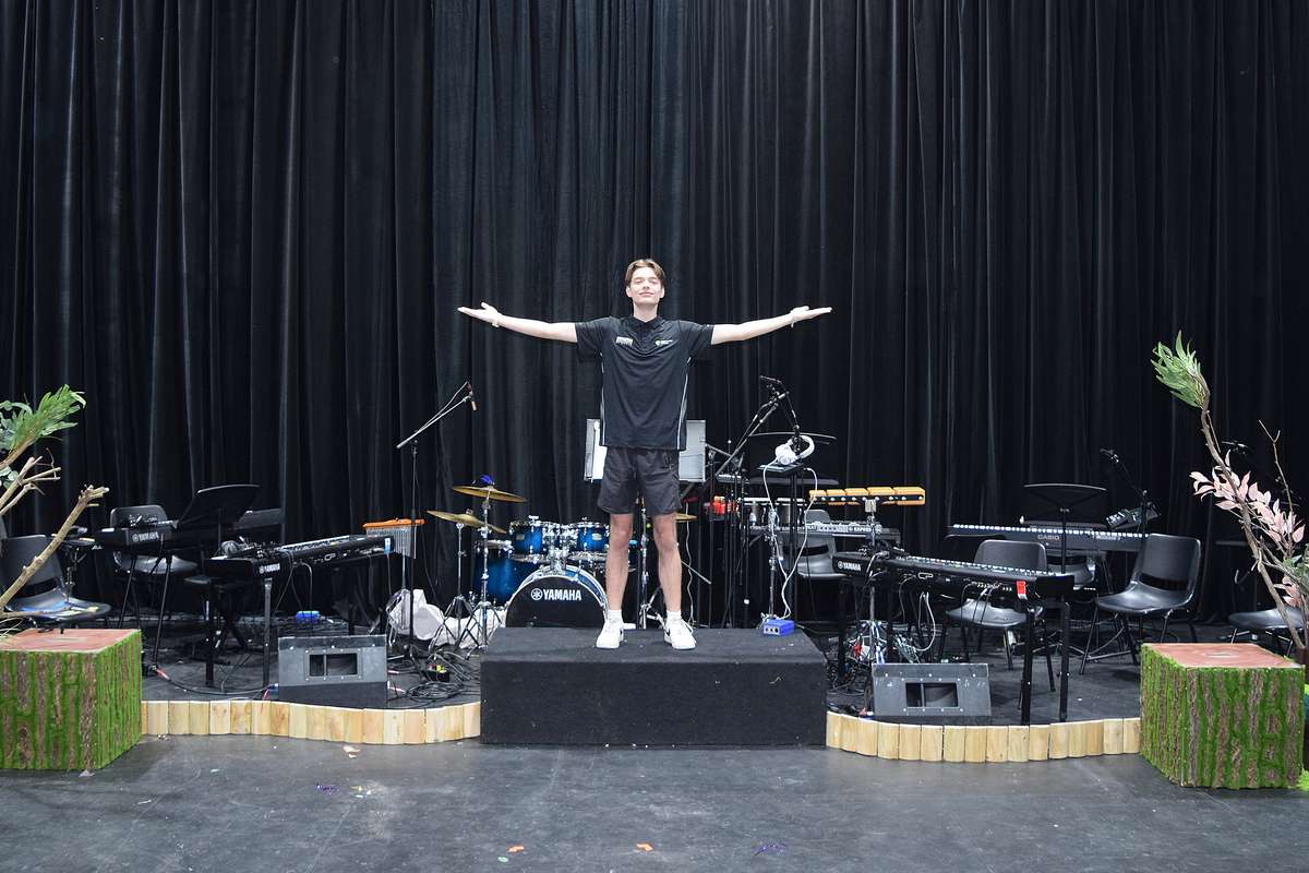 Image of young man with arms outstretched on a stage