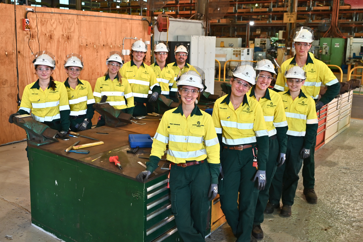Image of 11 young men and women in high visibility clothing and hard hats in a workshed setting