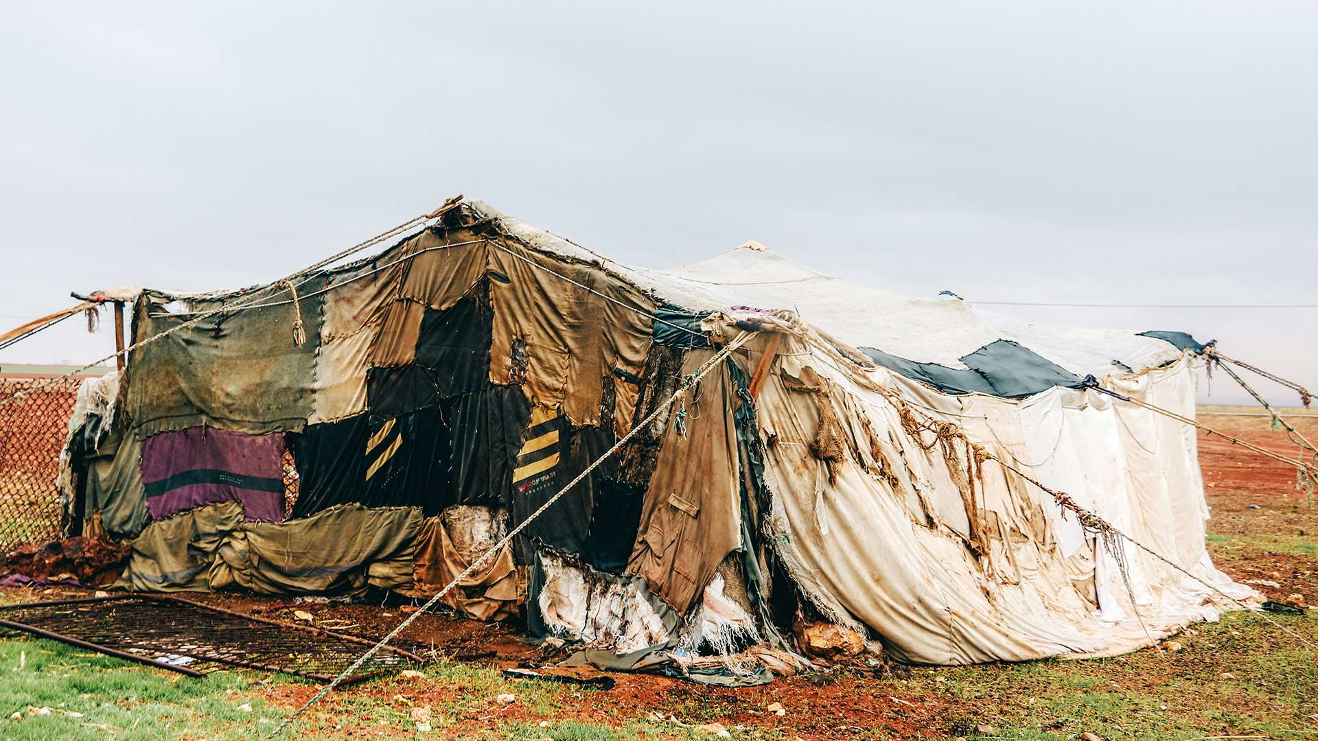 Large dirty tent structure made with mix match blankets, sheets and rope