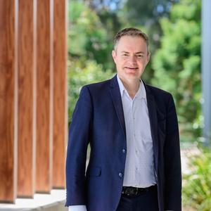 Paul Hodgson standing outside the Centre for Hydrogen and Renewable Energy in a suit smiling at the camera