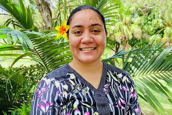 International student Pauline  Savea Motunuu from Samoa in a floral polo and flower in the hair with hands crossed in front smiling at the camera