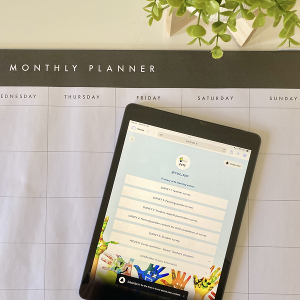 An iPad showing the Primary Art Online web space sitting on top of a Monlthy Planner