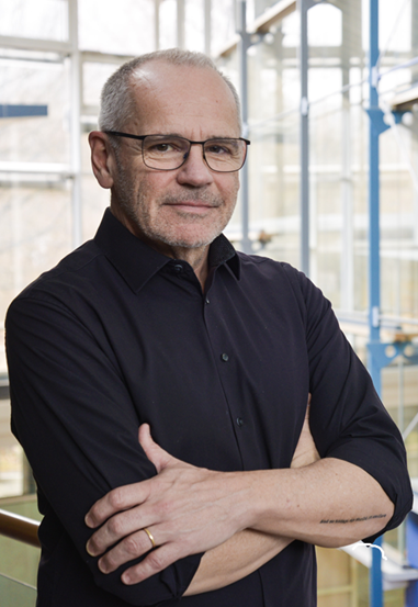 Alumnus Heiner Boettger wearing glasses and arms crossed.