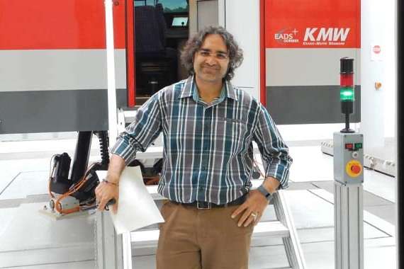 Associate Professor Anjum Naweed standing in front of a rail driving simulator