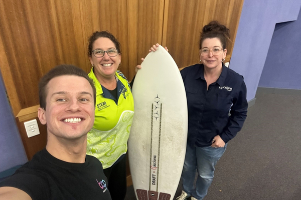Scott Millar_Associate Professor Linda Pfeiffer_Renee Mooney holding a surfboard and smiling at camera