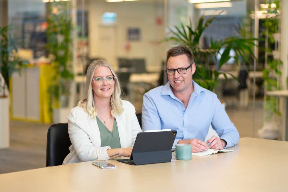 A male and female student smiling with a laptop open
