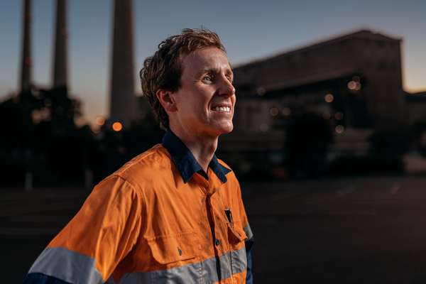 Mining student in PPE standing in a mine site carpark at dusk smiling