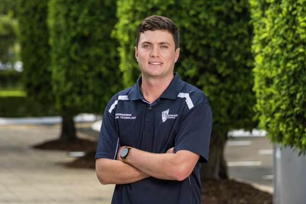 Rhett Lamperd standing in front of hedges smiling at the camera