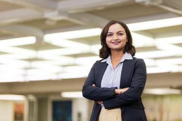 Richa Neupane, a business student standing smiling at the camera with their arms crossed.