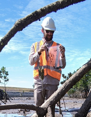 Rory Mulloy in PPE collecting samples from mudflats