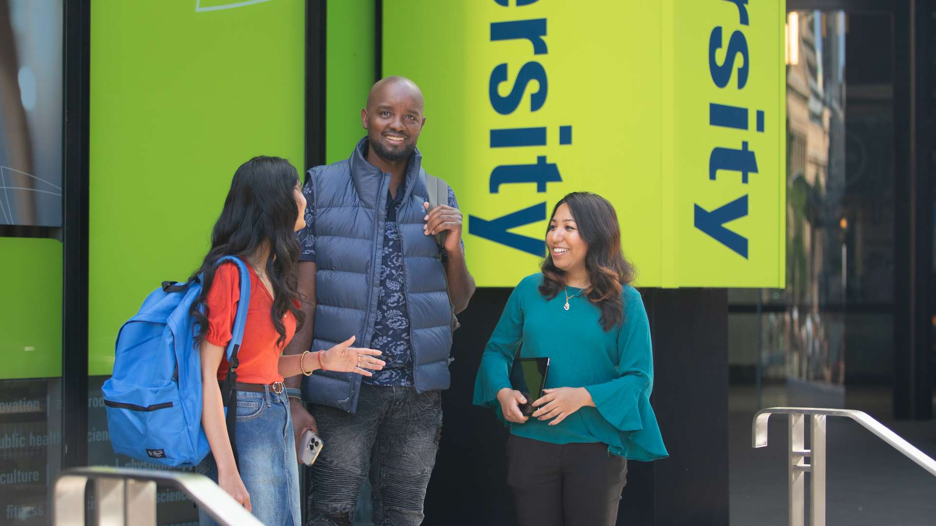 Three international students standing outside the Brisbane Campus together with backpacks