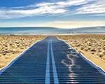 A blue mat running from the top of the beach to the shoreline that allows wheelchairs to drvie on the beach