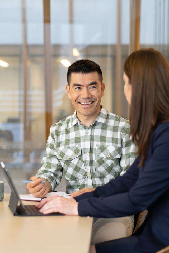 Two students in a corporate setting chatting with a laptop open