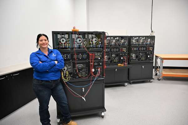 Young woman stands in front of electrical equipment