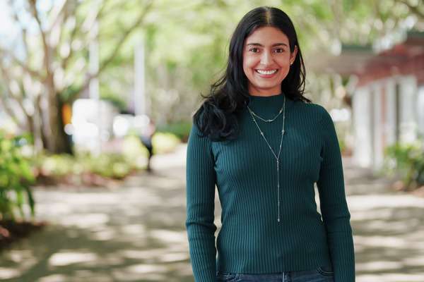 International student smiling at the camera with trees above them