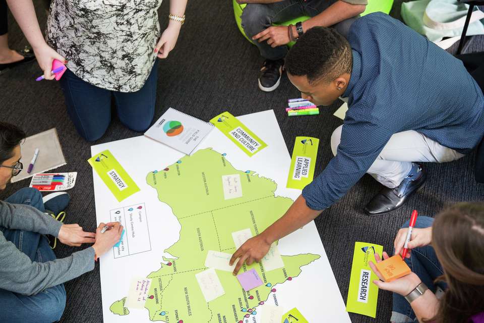 A group of social innovation students placing sticky notes on a map