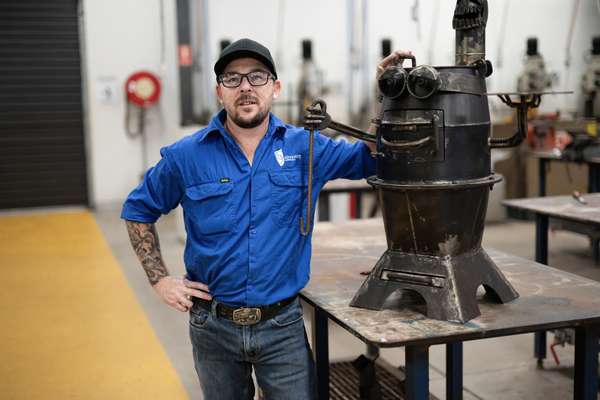 Image of man in blue shirt standing next to boilermaker