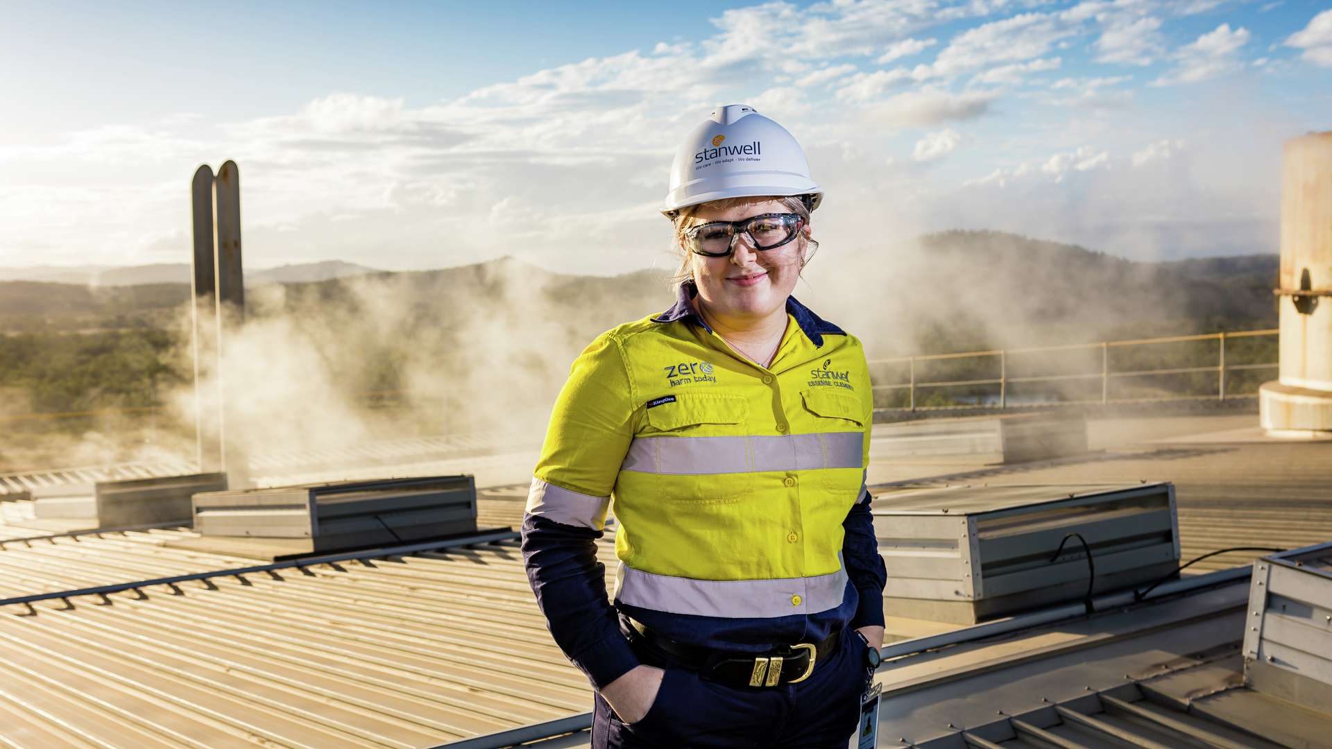 A Stanwell worker in high vis and a hard hat standing on the rooftop of a hydrogen plant