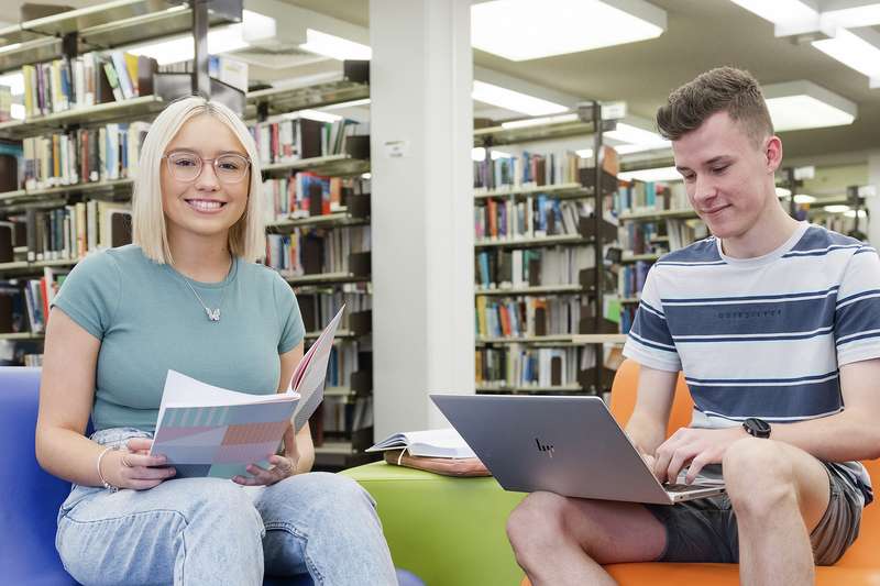 Two students study together in the library.