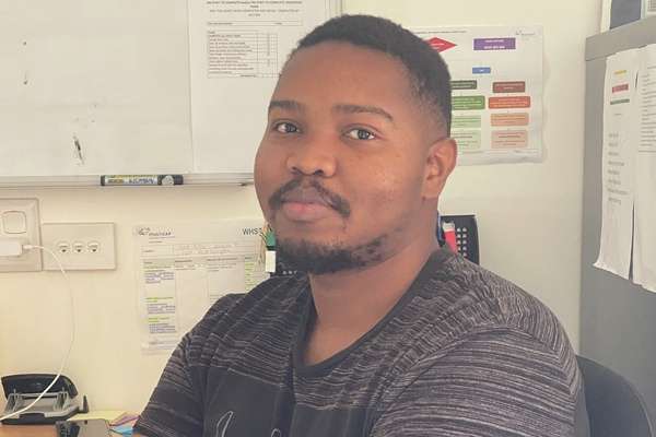 International student Steven Kunege from Tanzania sitting down in an office crossing their arms