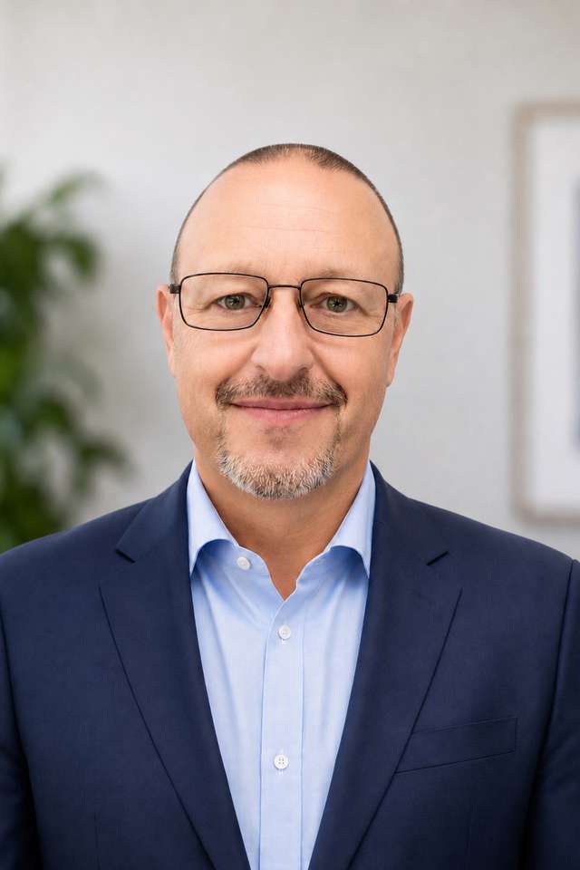 Alumnus Steven Menczel wearing a suit and glasses