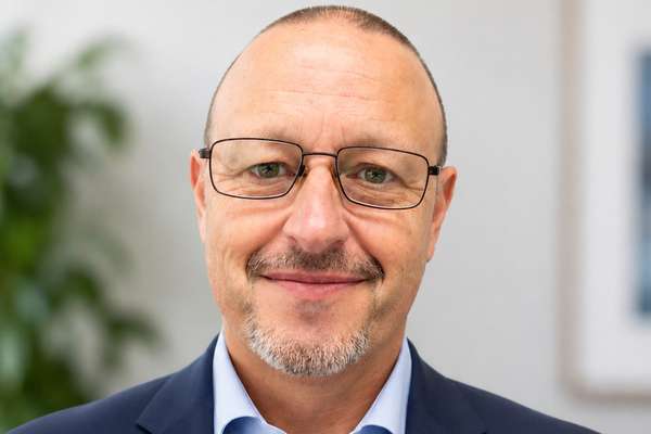 Alumnus Steven Menczel wearing a suit and glasses