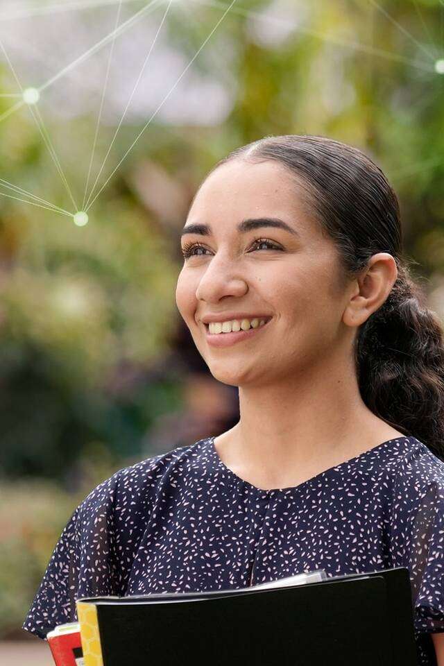 Tyla stands on campus looking into the distance with digital web graphics super imposed on the image.