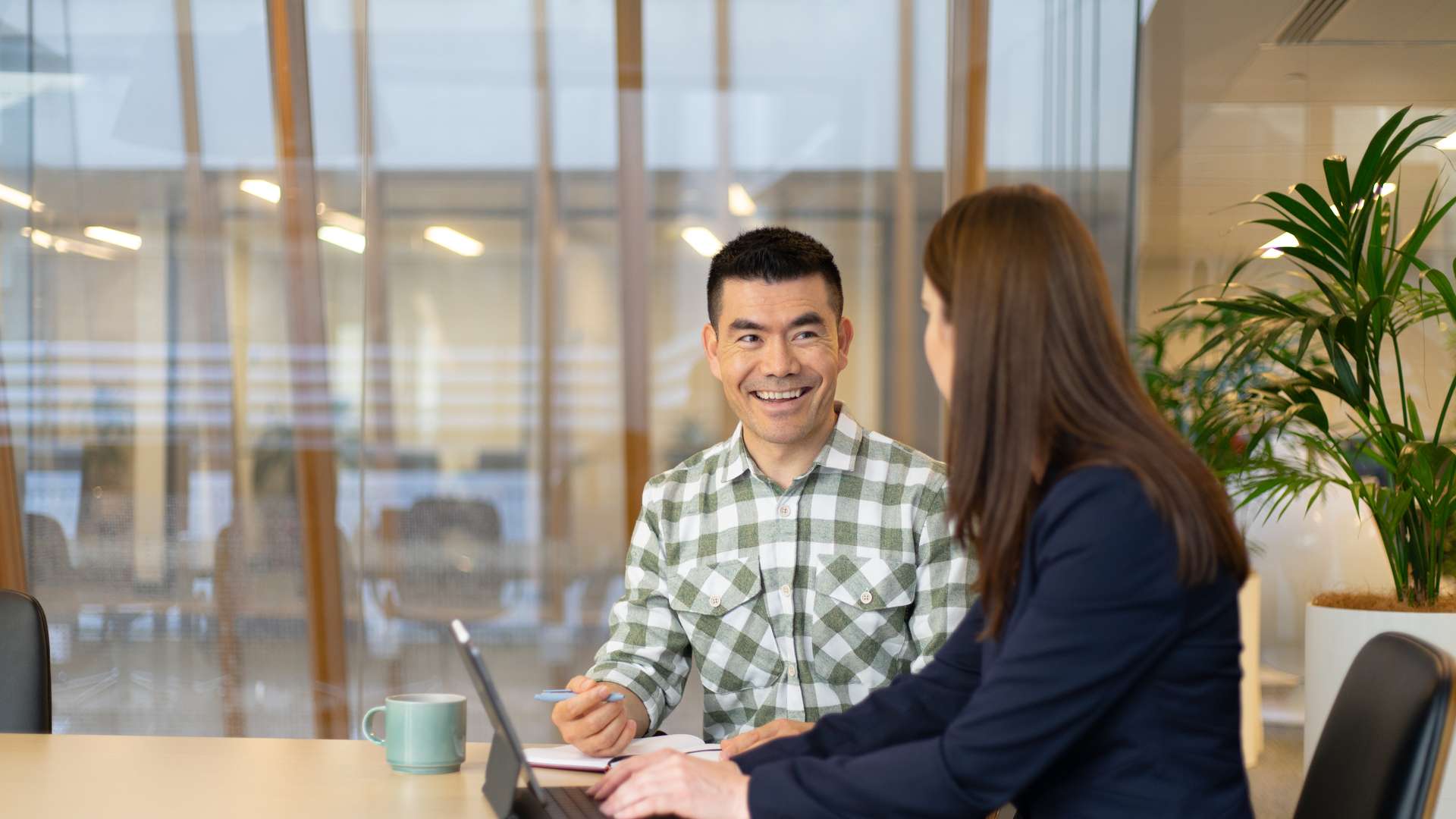 Two students in a corporate setting chatting with a laptop open