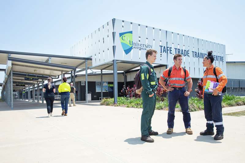 Three TAFE students chat in a group outside the TAFE Trade Training Centre.