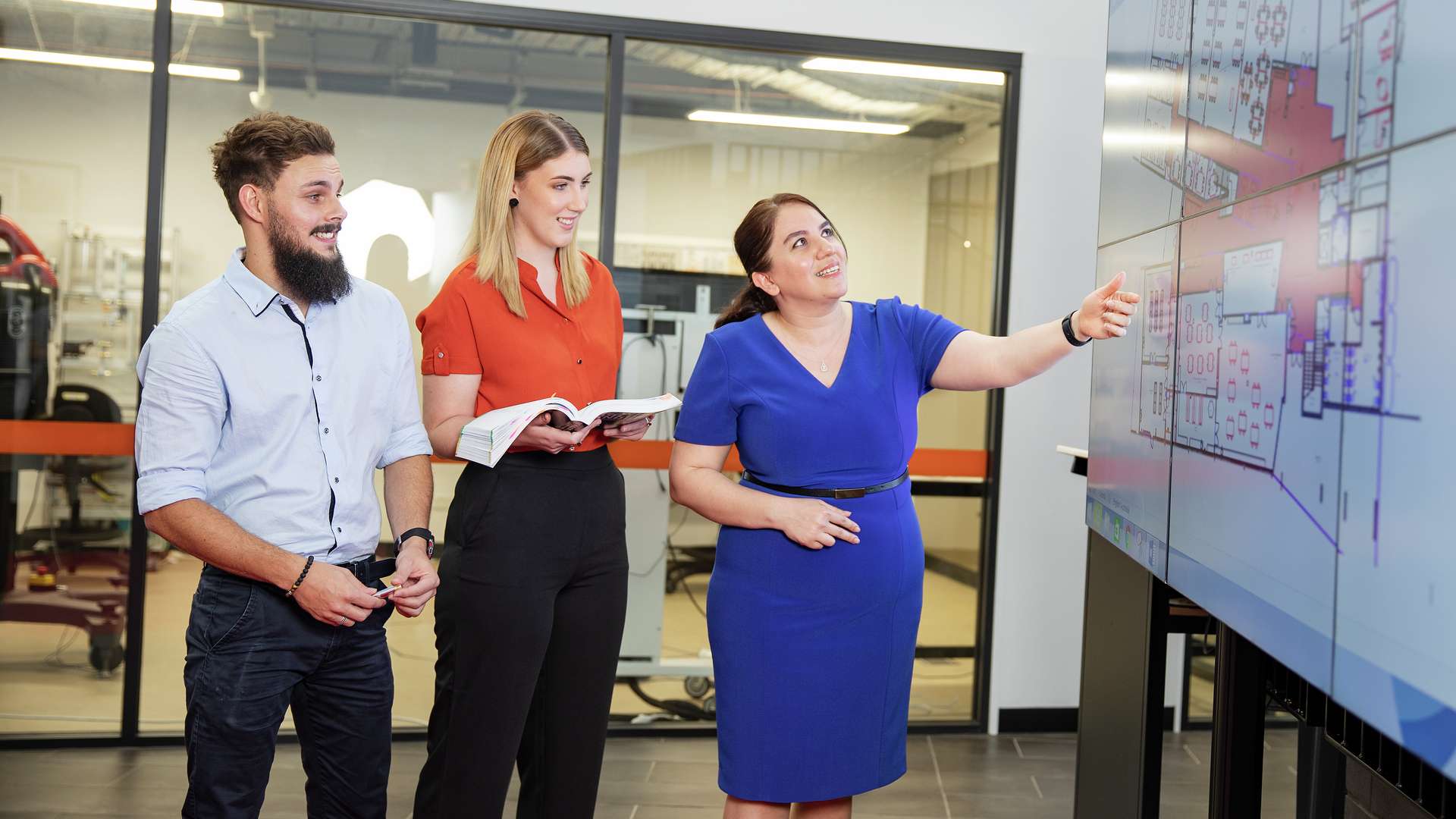 Students and a lecturer gesturing to a building design on a large screen