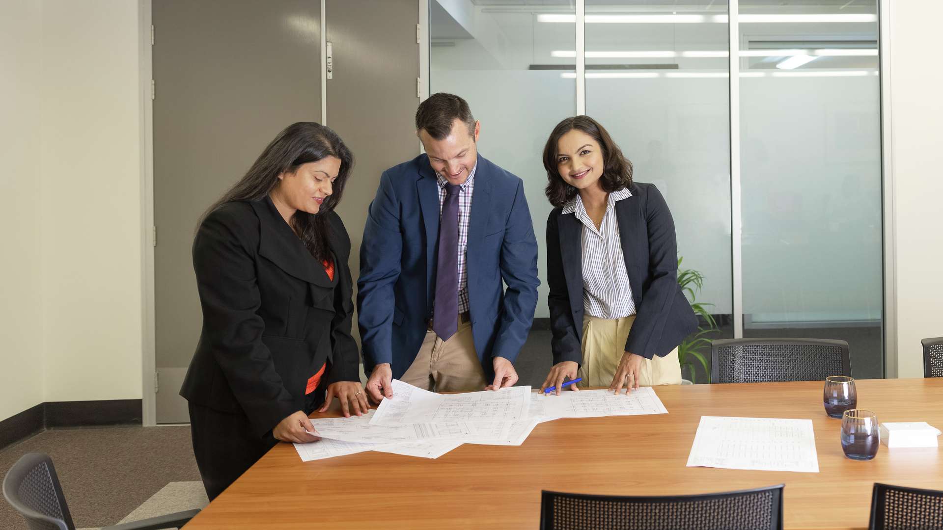 CQU Construction Management students look over construction plans whilst standing at boardroom table in preparation for a meeting