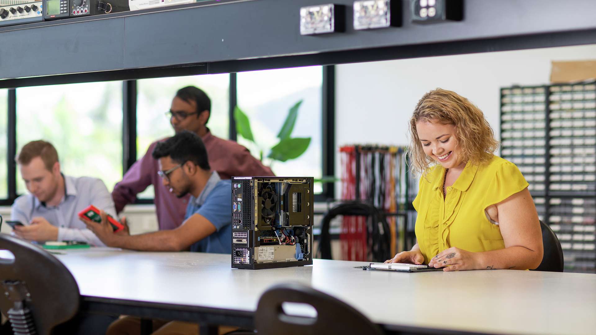 Information technology students examine equipment and discuss with their lecturer.